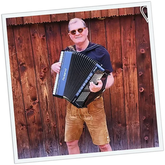 Keyboarder der Hochzeitsband und Partyband aus München und Bayern mit Lederhose, Mikrofon und Holzhintergrund