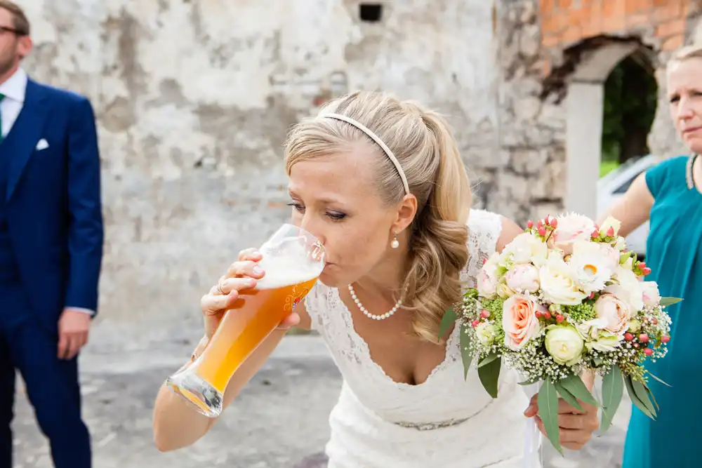 Braut mit Weißbier beim Feiern ihrer Hochzeitsparty in Ramsau in Bad Heilbrunn mit der Hochzeitsband IsarSix aus München und Bayern. Die Partyband für Hochzeit.