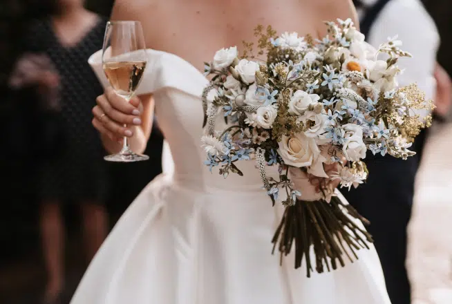 Das Bild zeigt eine Braut in weißem Brautkleid mit weinglas und Brautstrauß in der alten Gaertenerei in Taufkirchen in Muenchen, in der die Hochzeitsband aus München und Bayern in der Alte Gaertnerei Taufkirchen eine Hochzeit begleitet.