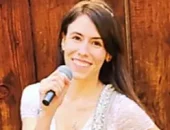 Kontaktbild von Evi, Sängerin der Partyband und Hochzeitsband München und Bayern mit Mikrofon im Dirndl und Holzhintergrund